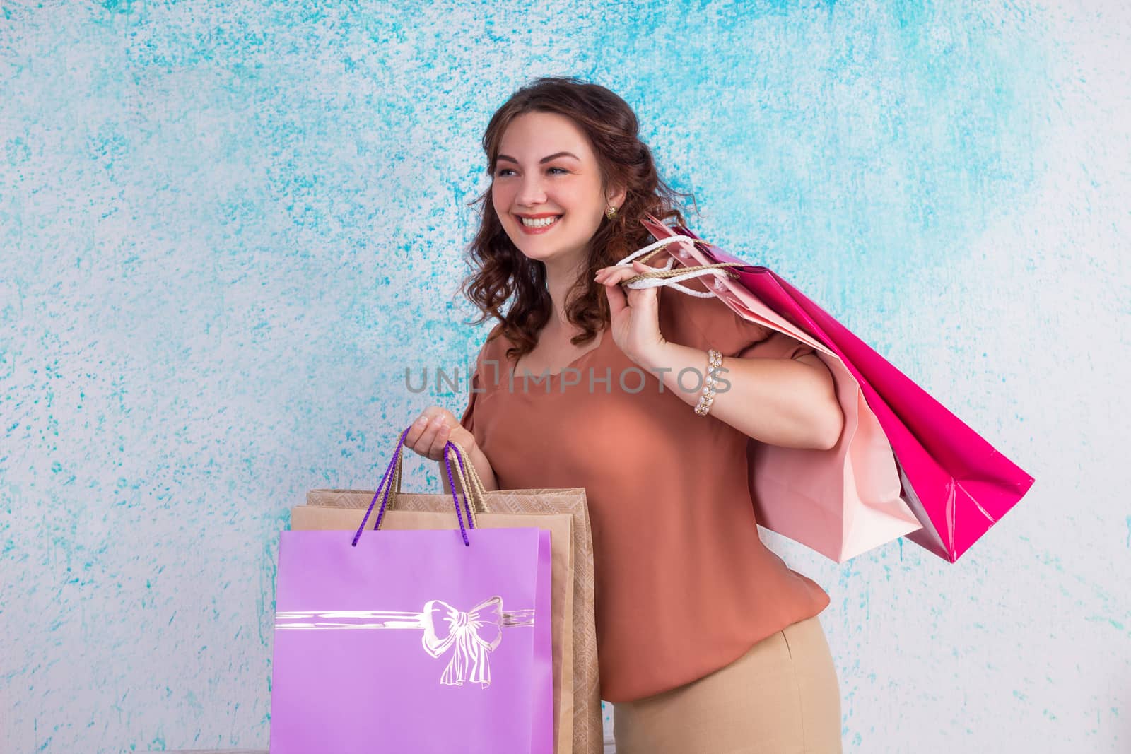 Happy smiling woman at shopping holding colourful paper bags in both hands