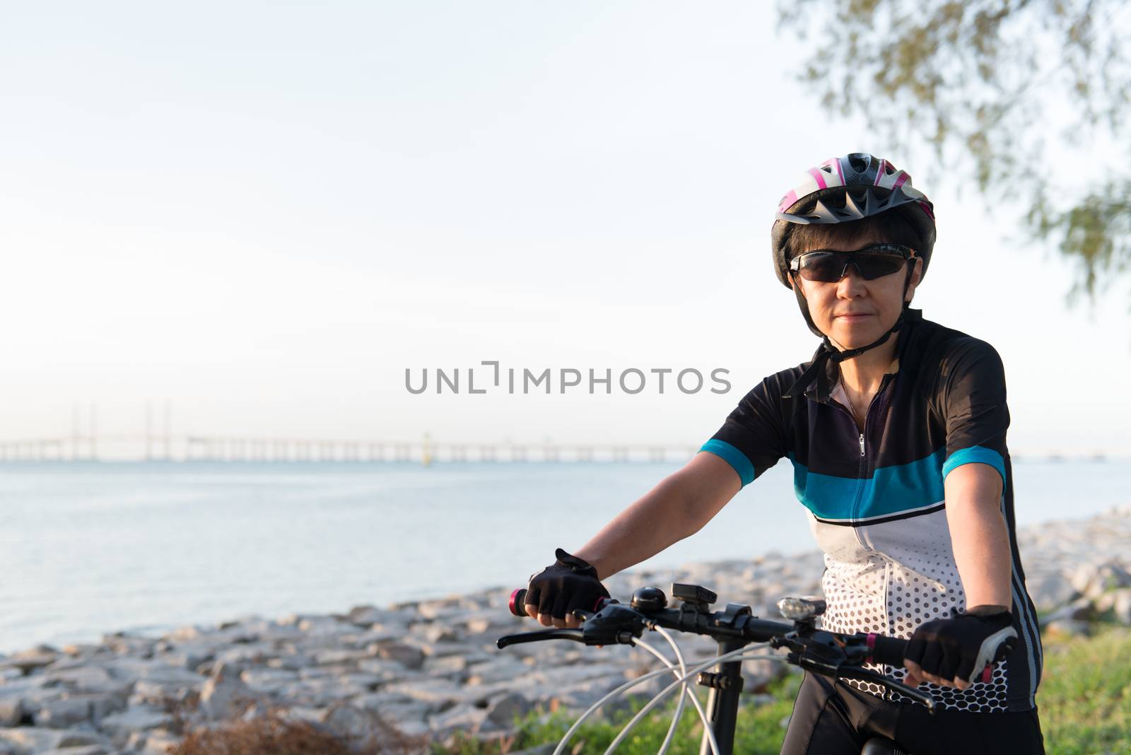 Joyful senior woman riding a bicycle by Kenishirotie