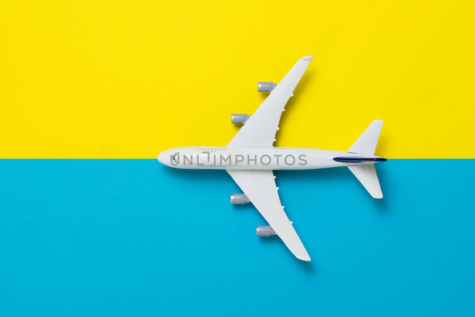 Miniature airplane model on blue and yellow background for travel theme