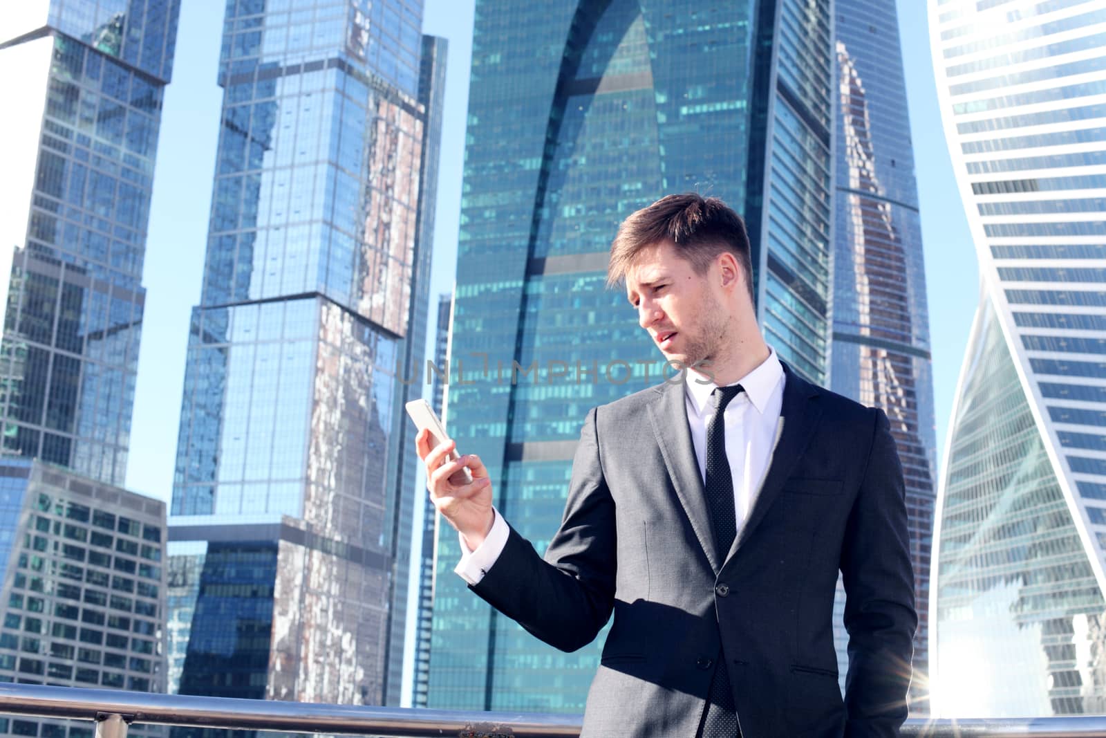 Businessman using smartphone on skyscraper background