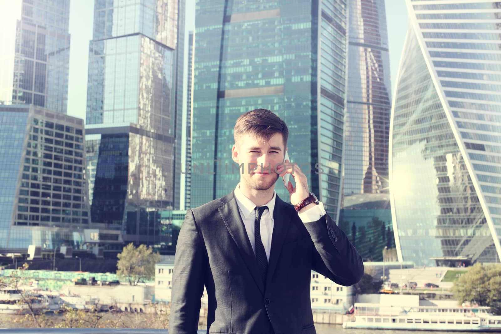 Businessman talking on the phone on skyscraper background