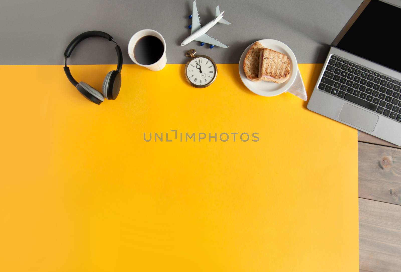 Business accessories including laptop, clock with grilled sandwich view from above