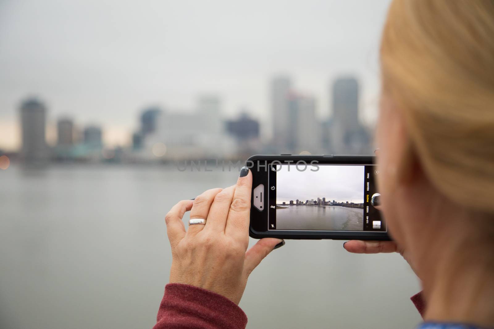 Woman Taking Pictures of The New Orleans Skyline with Her Smart Phone by Feverpitched