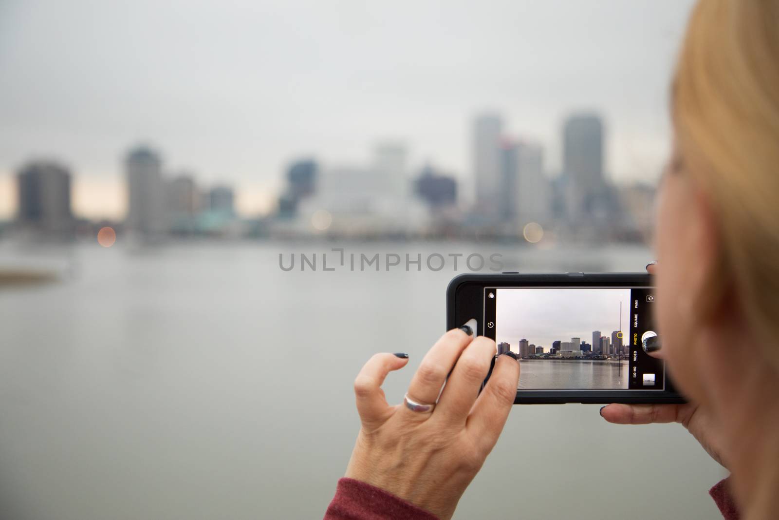 Woman Taking Pictures of The New Orleans Skyline with Her Smart Phone by Feverpitched