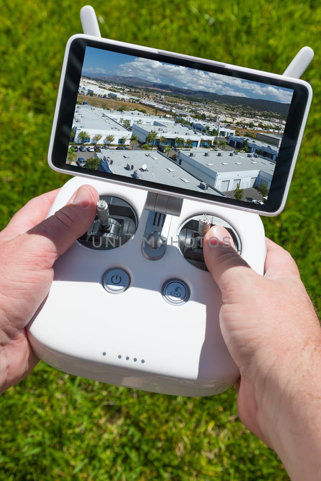 Hands Holding Drone Quadcopter Controller With Indutrial Buildings on Screen.