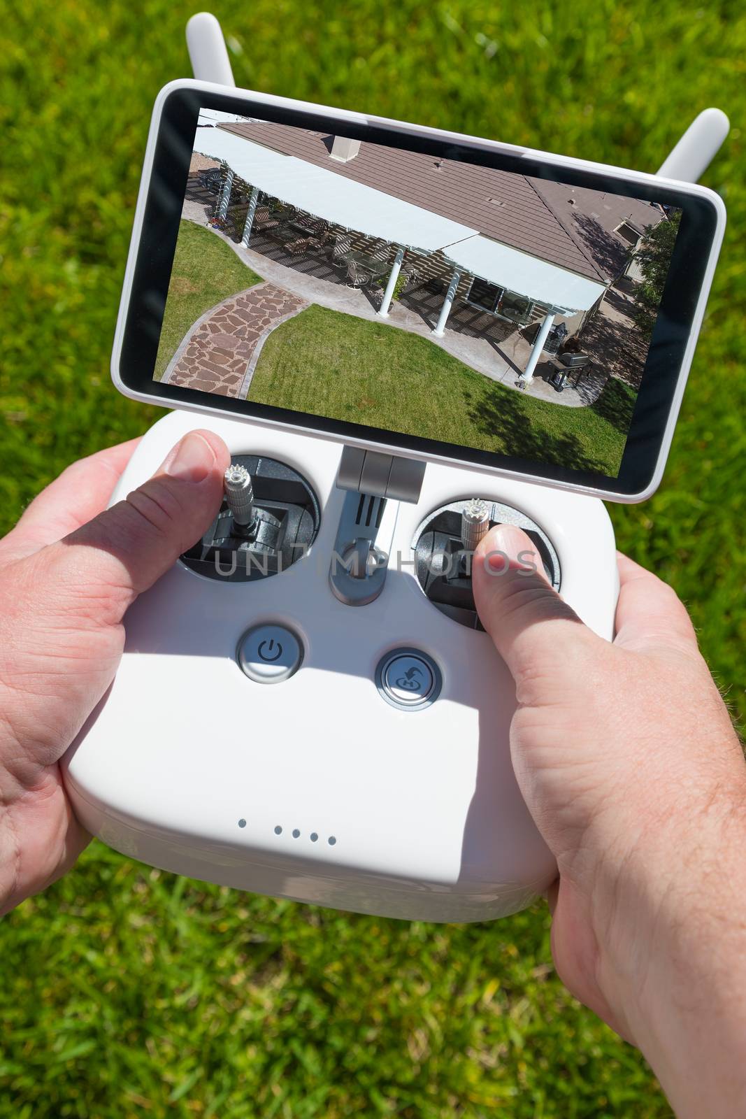 Hands Holding Drone Quadcopter Controller With Overhead of House on Screen. by Feverpitched