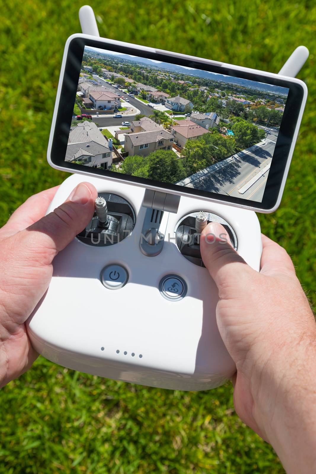 Hands Holding Drone Quadcopter Controller With Residential Homes on Screen.