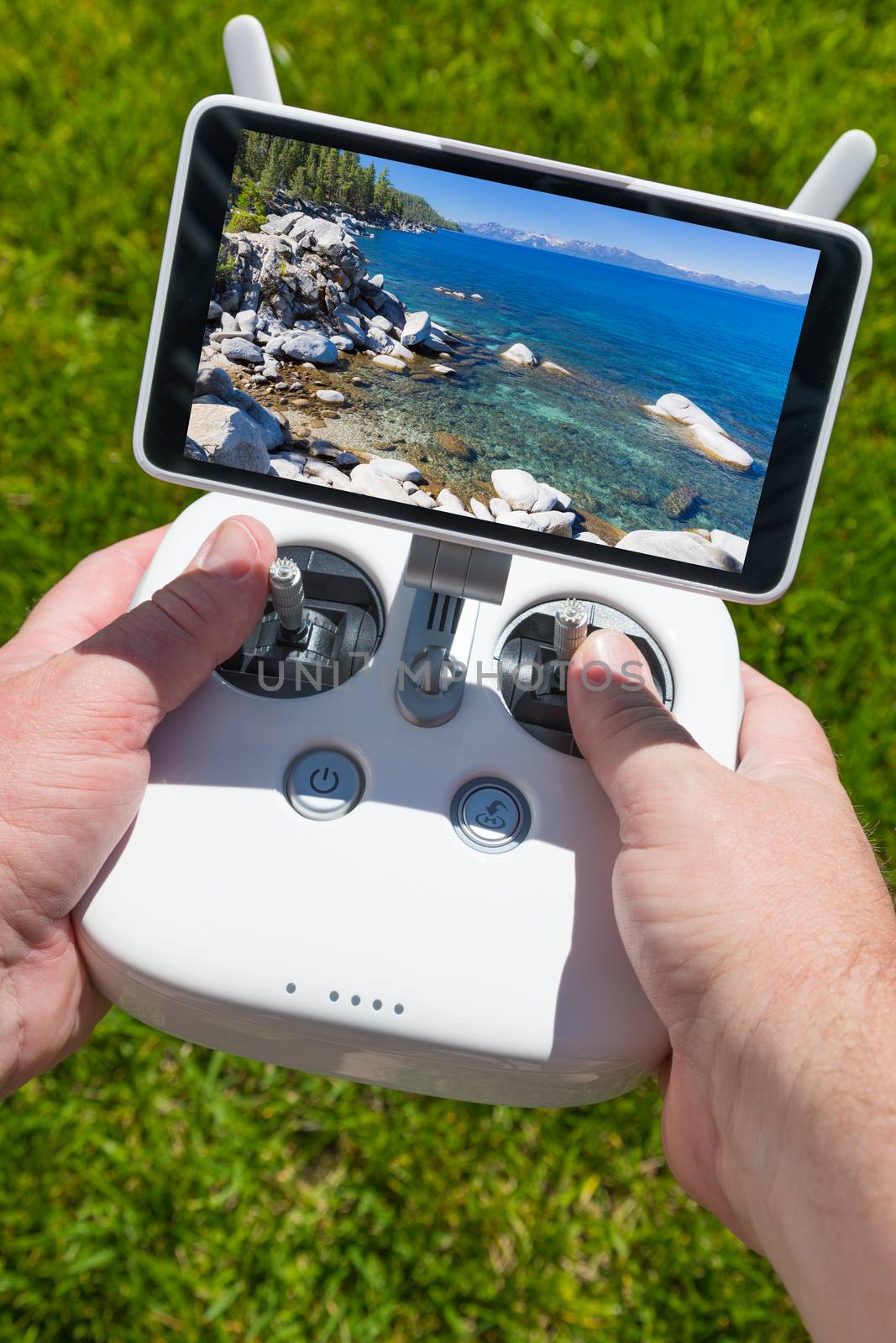 Hands Holding Drone Quadcopter Controller With Beautiful Lake View on Screen.
