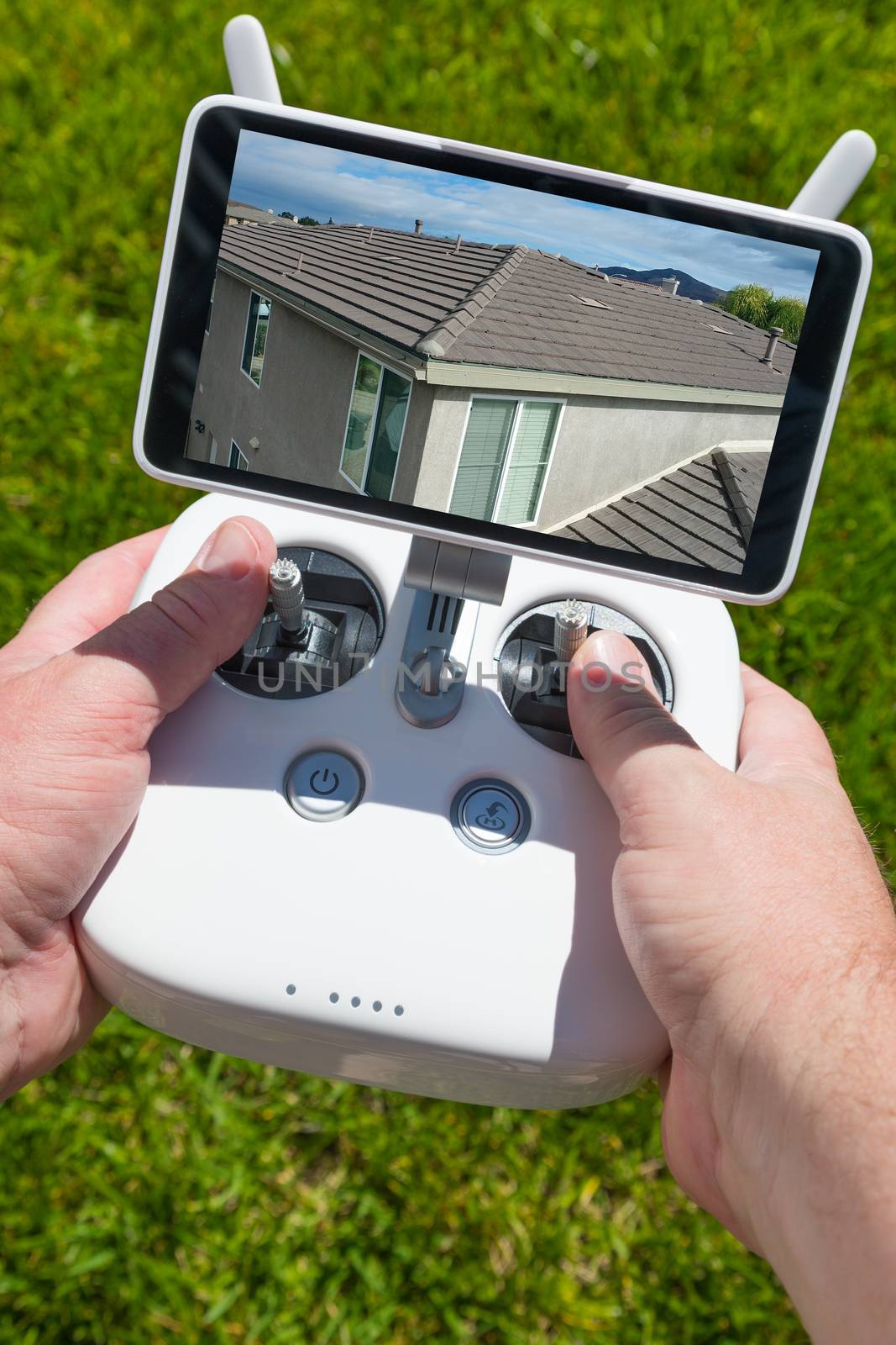 Hands Holding Drone Quadcopter Controller With Residential Roof Image on Screen.