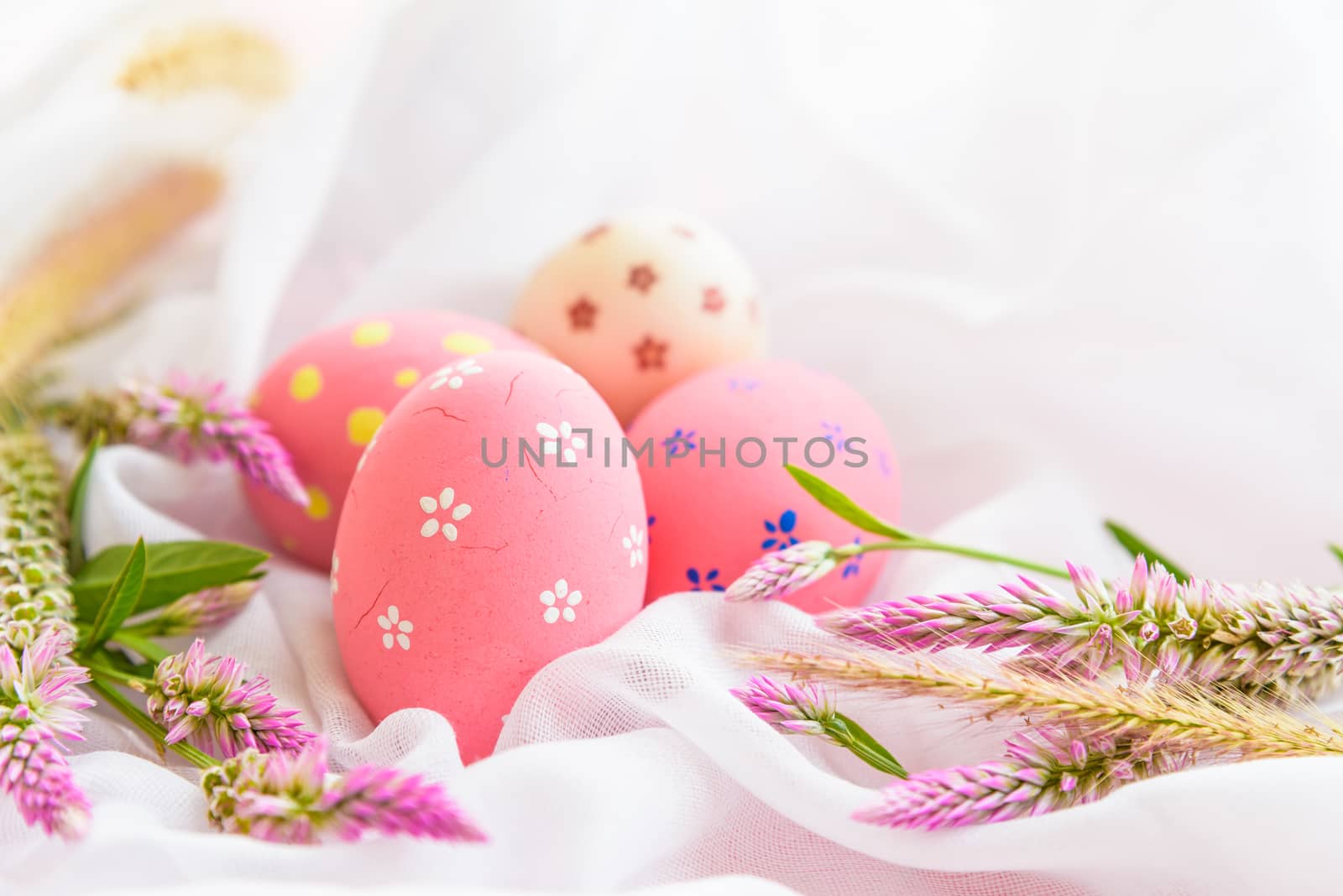 Happy easter! Colorful of Easter eggs in nest with flower,  paper star and Feather on white cheesecloth background.