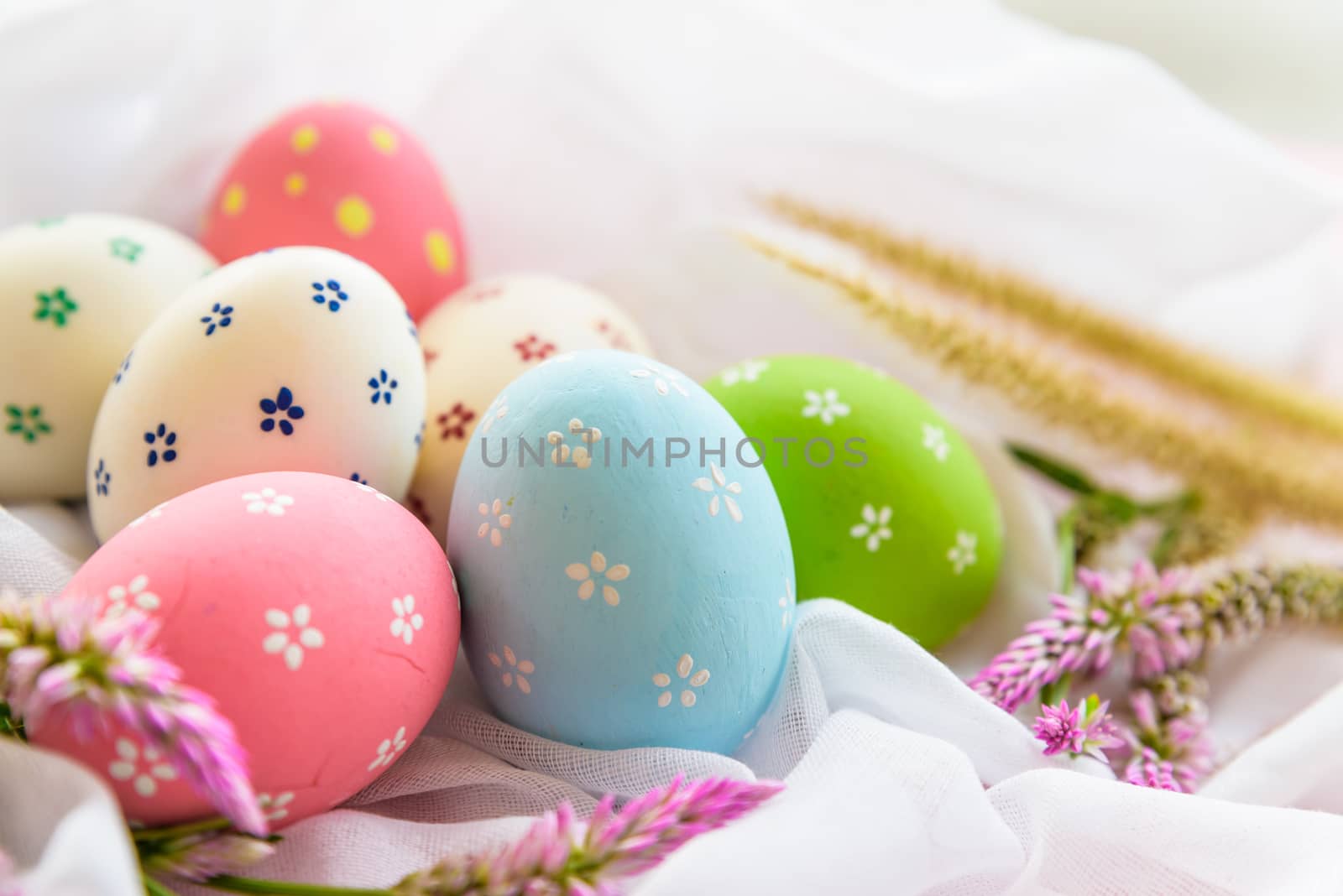 Happy easter! Colorful of Easter eggs in nest with flower,  paper star and Feather on white cheesecloth background.