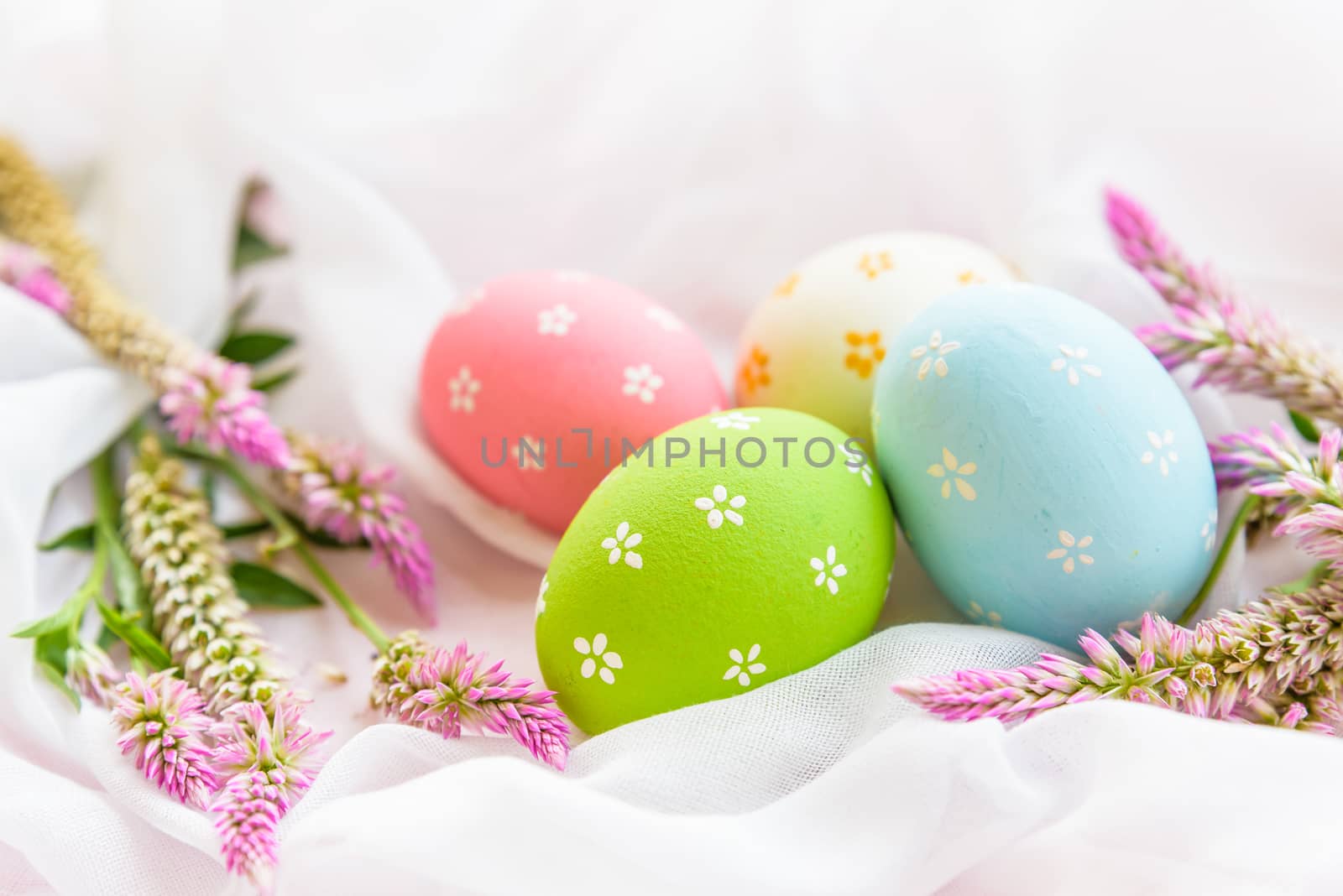 Happy easter! Colorful of Easter eggs in nest with flower,  paper star and Feather on white cheesecloth background.