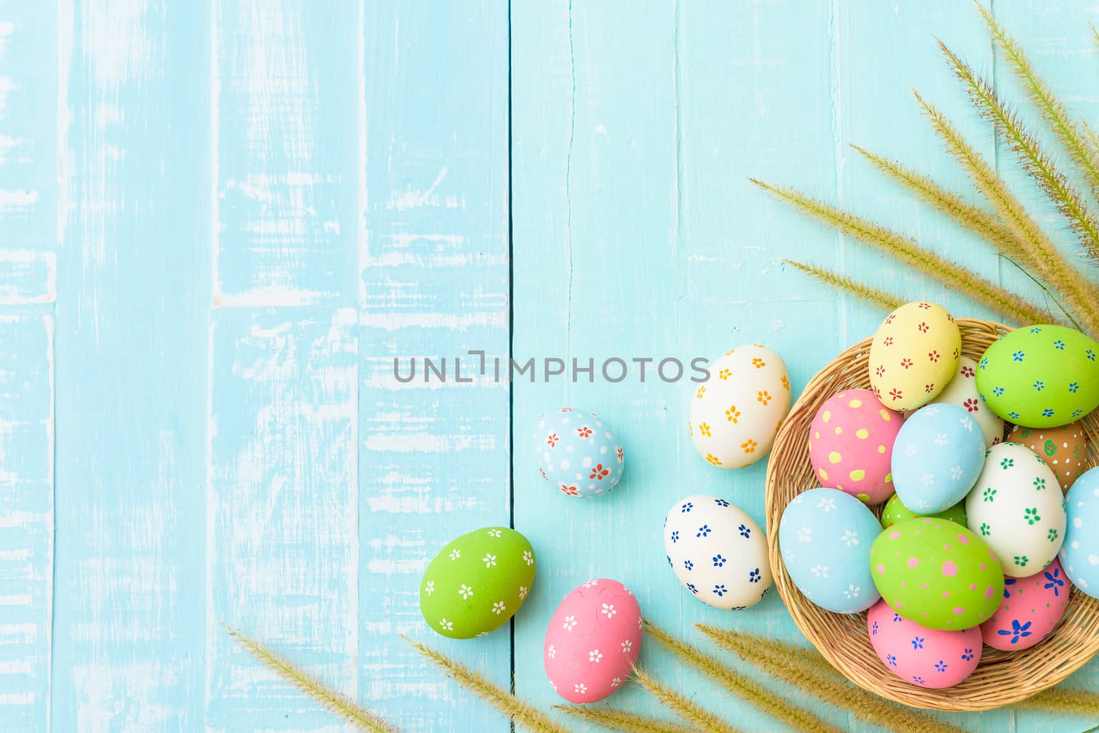 Happy easter! Colorful of Easter eggs in nest with paper star, flower and Feather on pastel color bright blue and white wooden background.