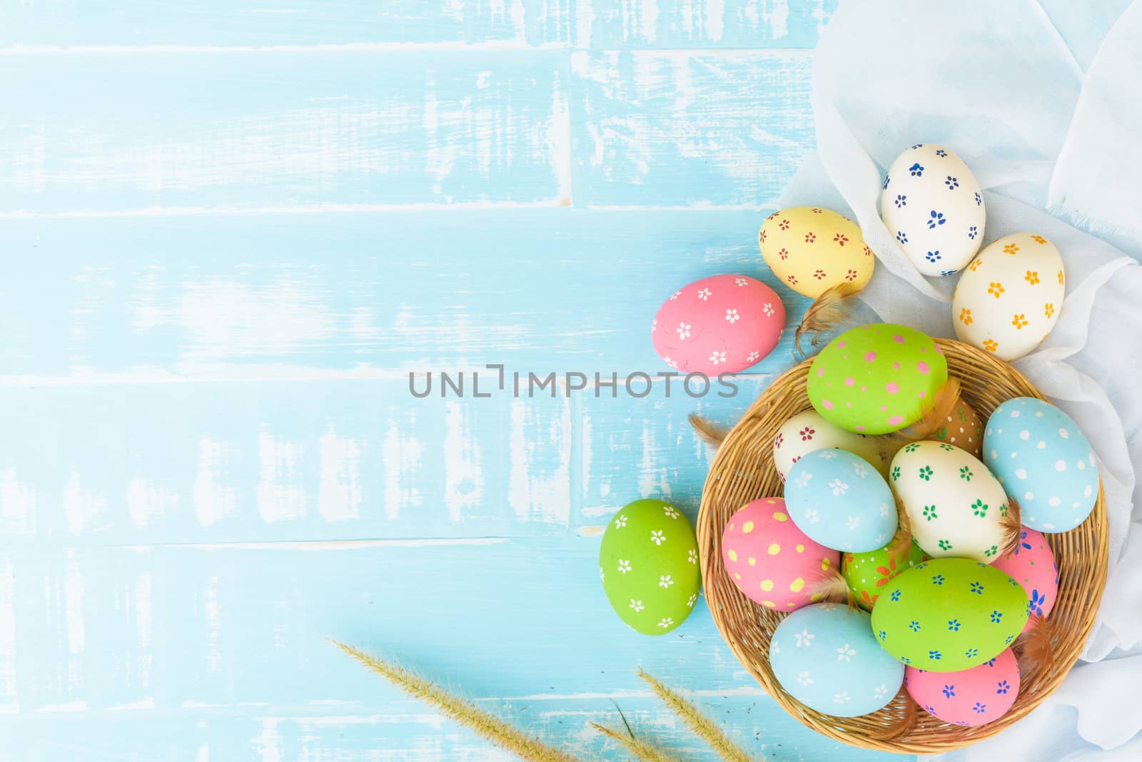 Happy easter! Colorful of Easter eggs in nest with paper star, flower and Feather on pastel color bright blue and white wooden background.