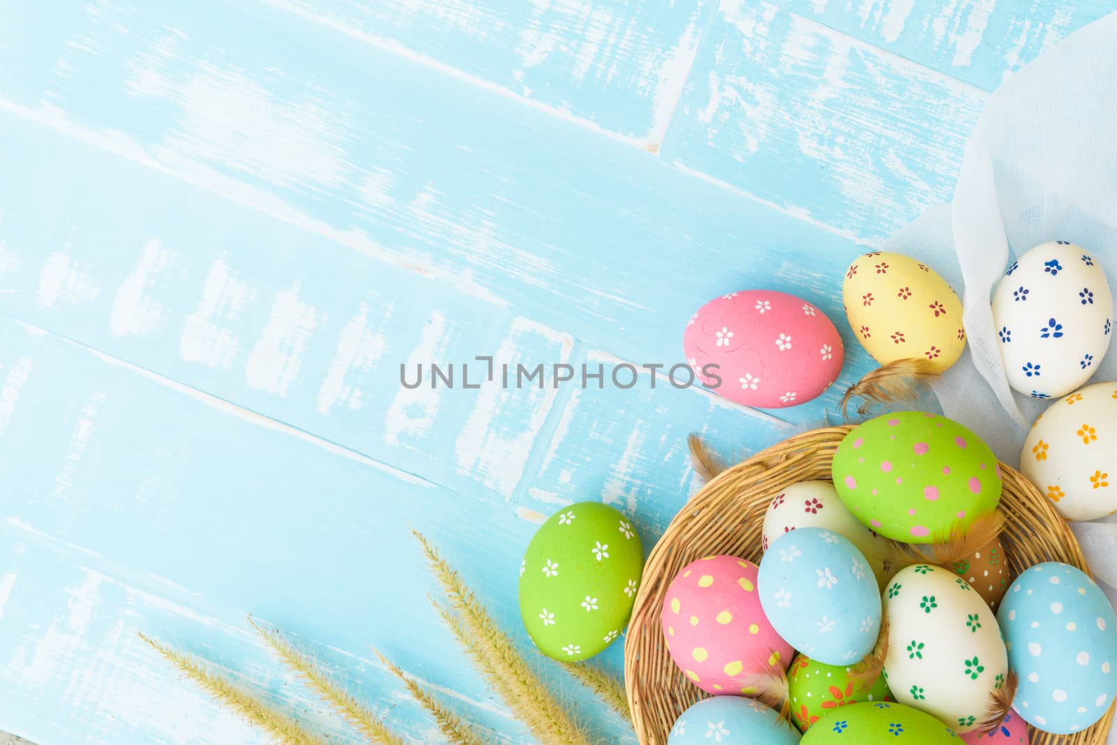 Happy easter! Colorful of Easter eggs in nest with paper star, flower and Feather on pastel color bright blue and white wooden background.