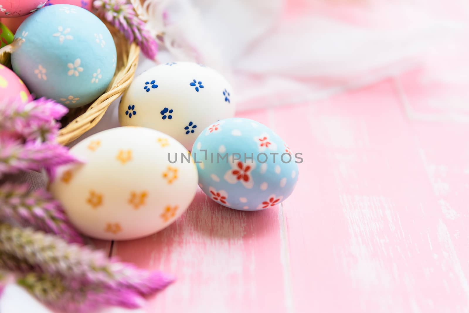 Happy easter! Colorful of Easter eggs in nest with paper star, flower and Feather on pastel color bright pink and white wooden background.