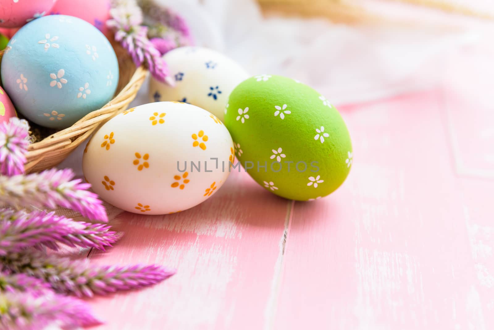 Happy easter! Colorful of Easter eggs in nest with paper star, flower and Feather on pastel color bright pink and white wooden background.