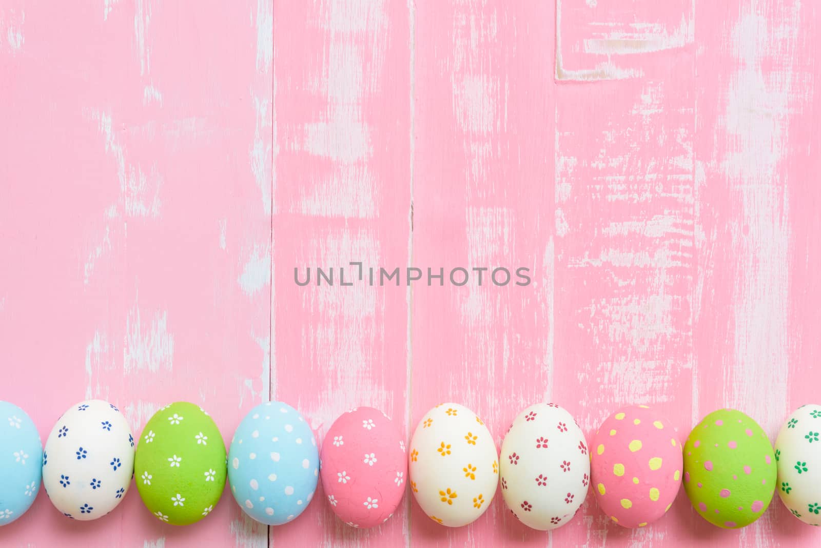 Happy easter! Row Easter eggs with colorful paper flowers on bright pink wooden background.