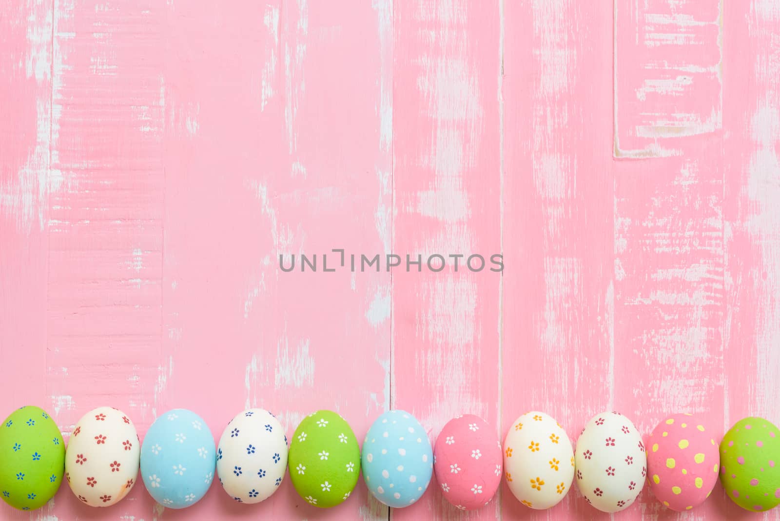 Happy easter! Row Easter eggs with colorful paper flowers on bright pink wooden background.