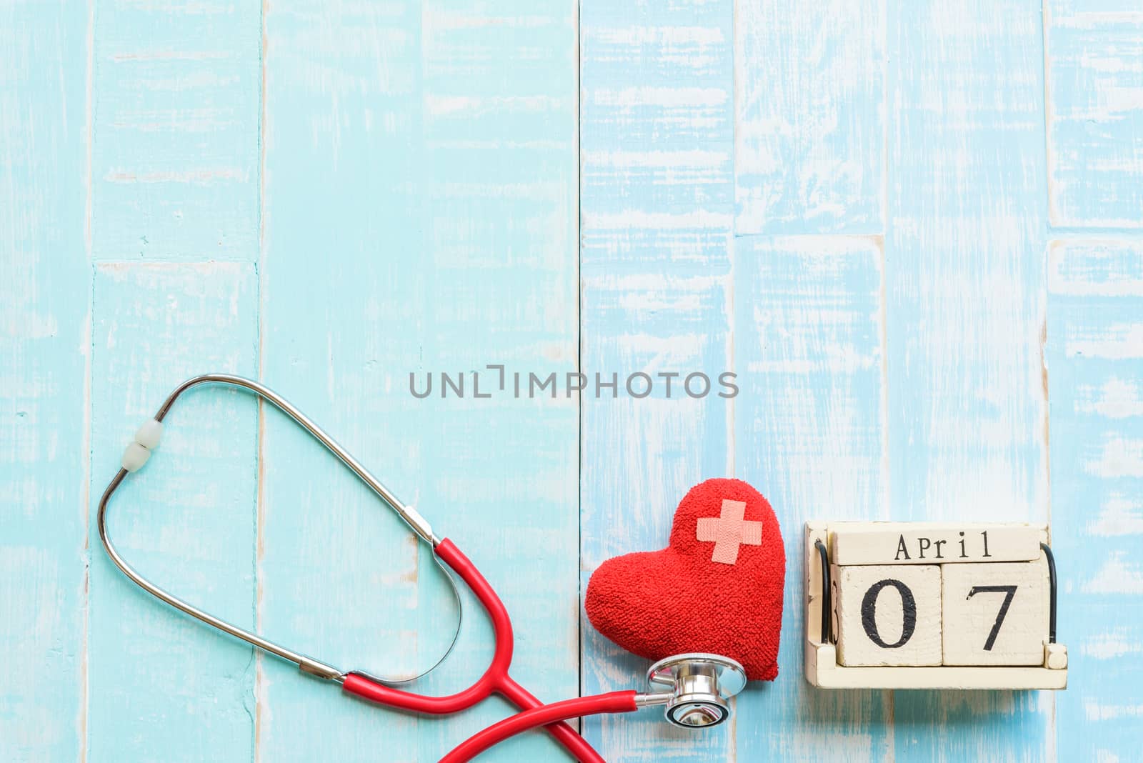 Wooden Block calendar for World health day, April 7. Healthcare and medical concept. Red heart with Stethoscope on Pastel white and blue wooden table background texture.