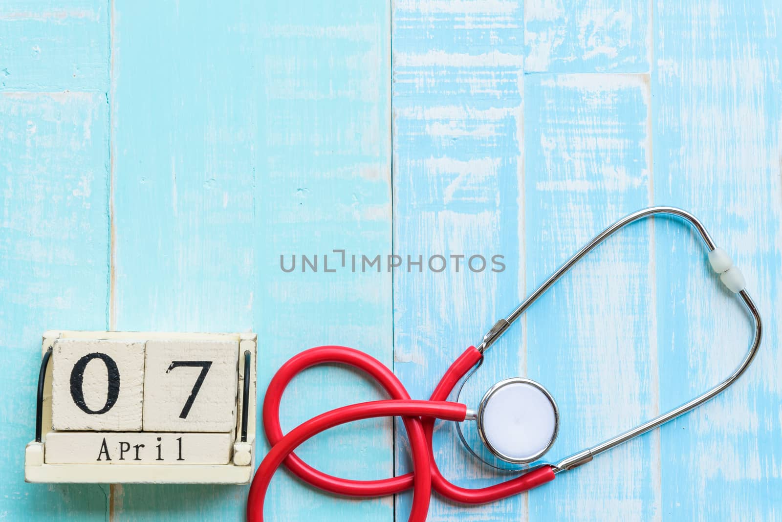 Wooden Block calendar for World health day, April 7. Healthcare and medical concept. Red heart with Stethoscope on Pastel white and blue wooden table background texture.