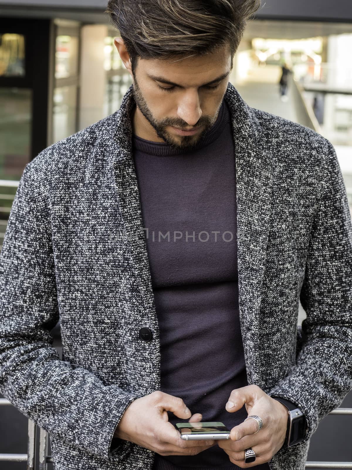 Handsome trendy man typing on cell phone by artofphoto