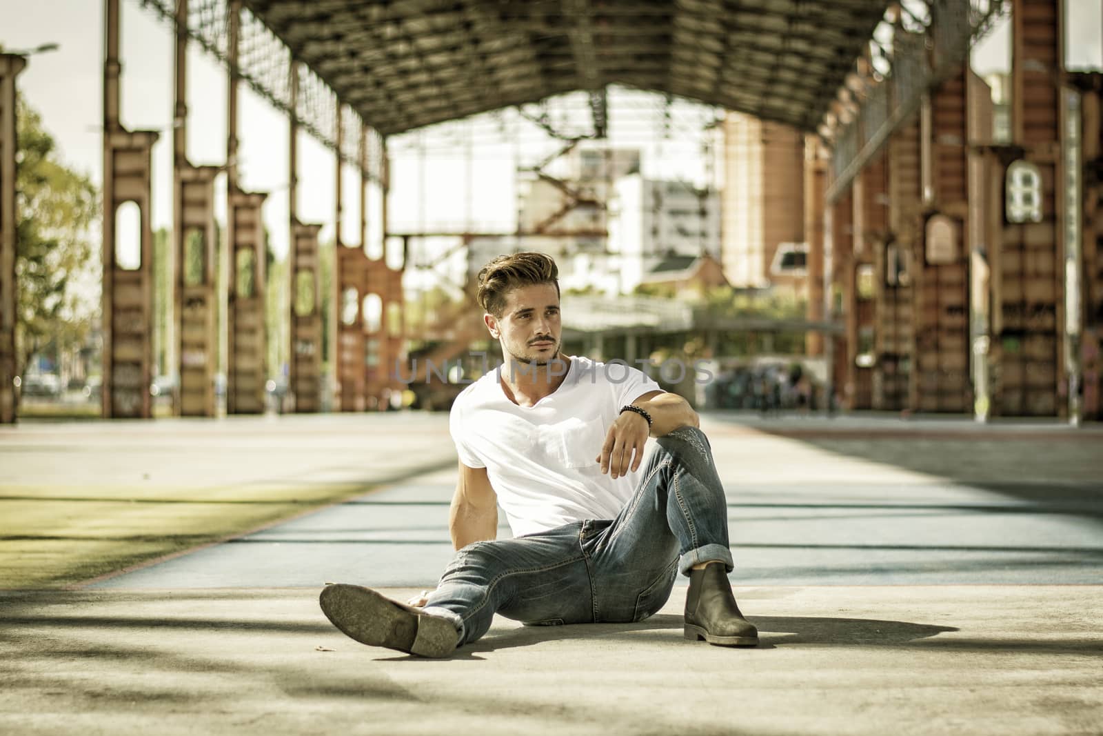 Attractive man in urban setting under big metal structure, a former industrial site