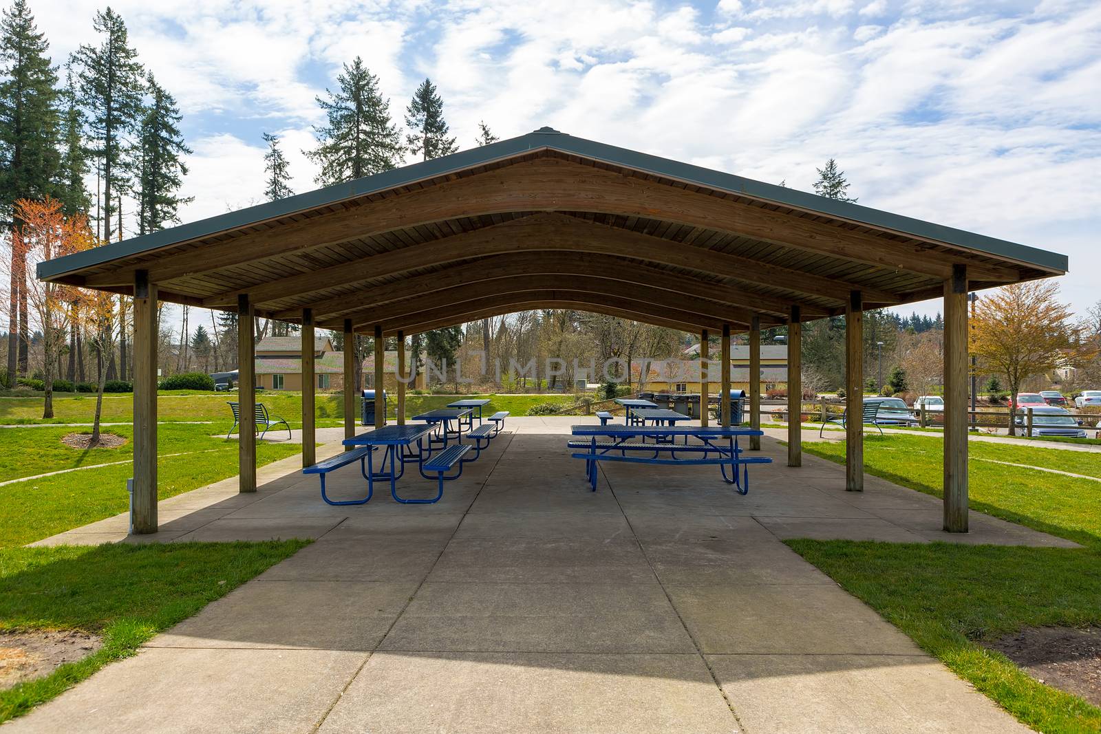 Picnic tables under wooden roof shelter structure in suburban neighborhood city park