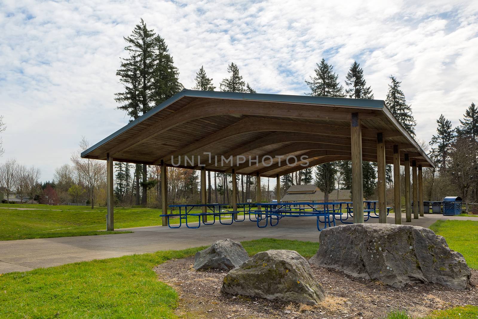 Picnic tables under wood shelter structure in suburban neighborhood city park