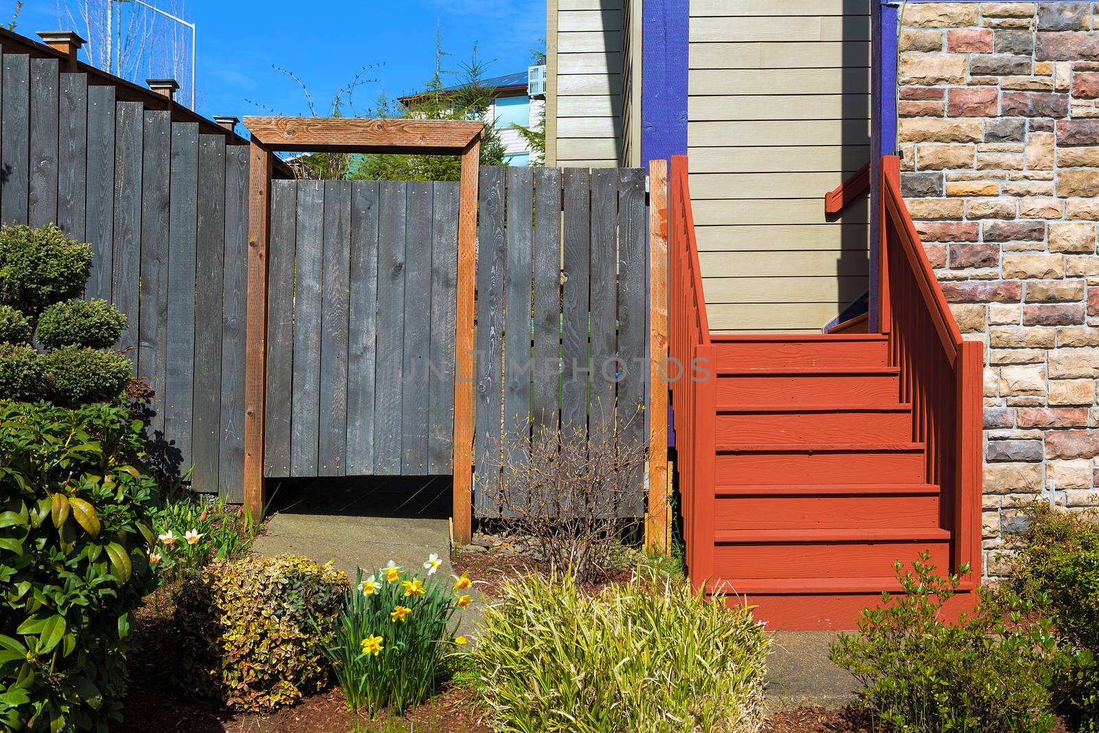 Home garden frontyard with plants wood fence gate colorful staircase sidings and stone wall