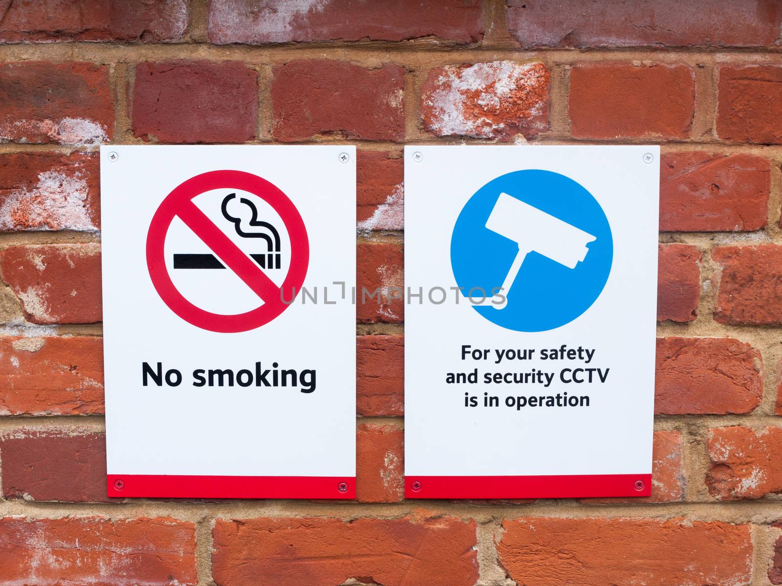 two signs at train station cctv no smoking; essex; england; uk