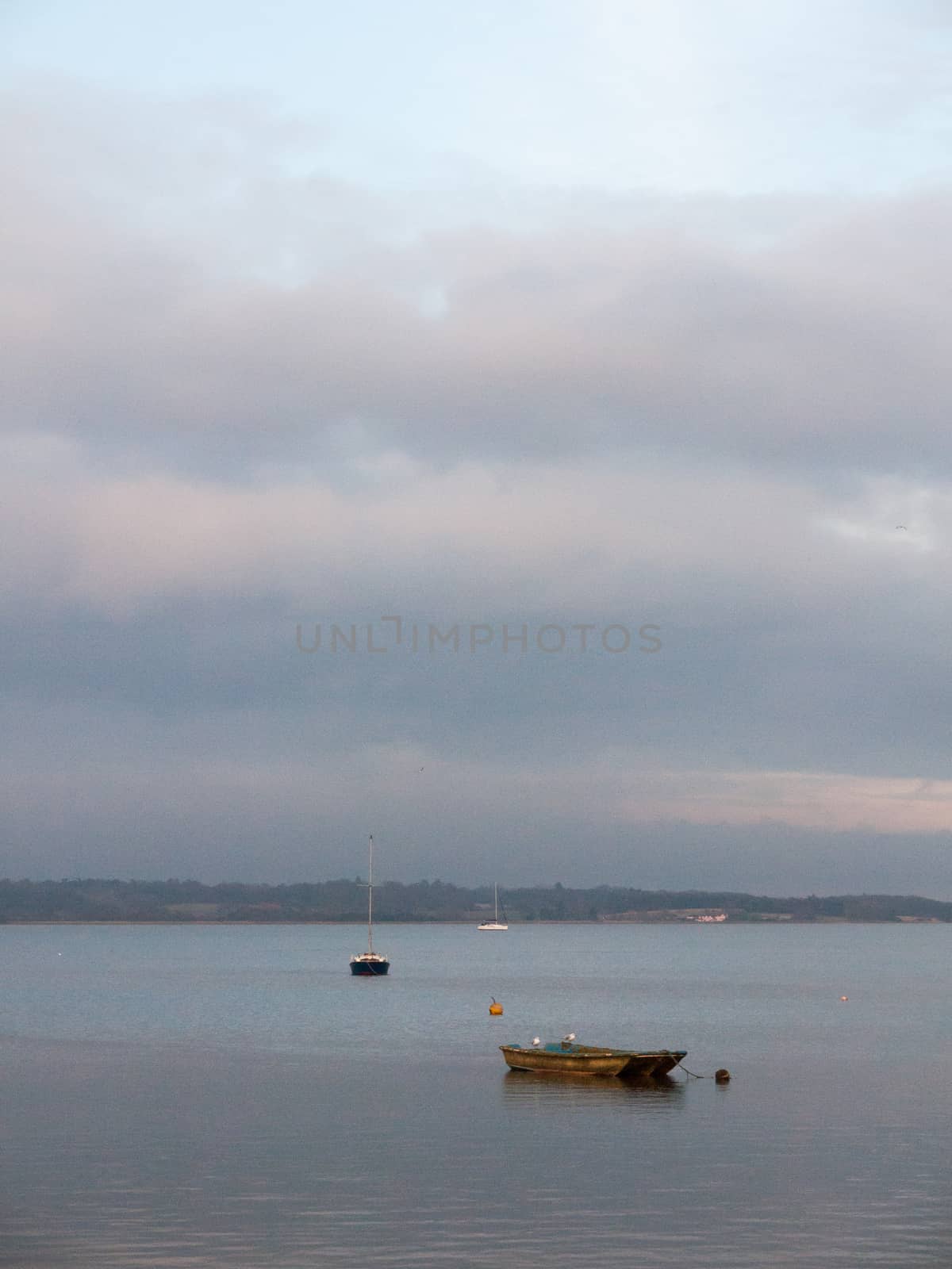 sunset over coast ocean bay water sky sea boats docks moored; essex; england; uk