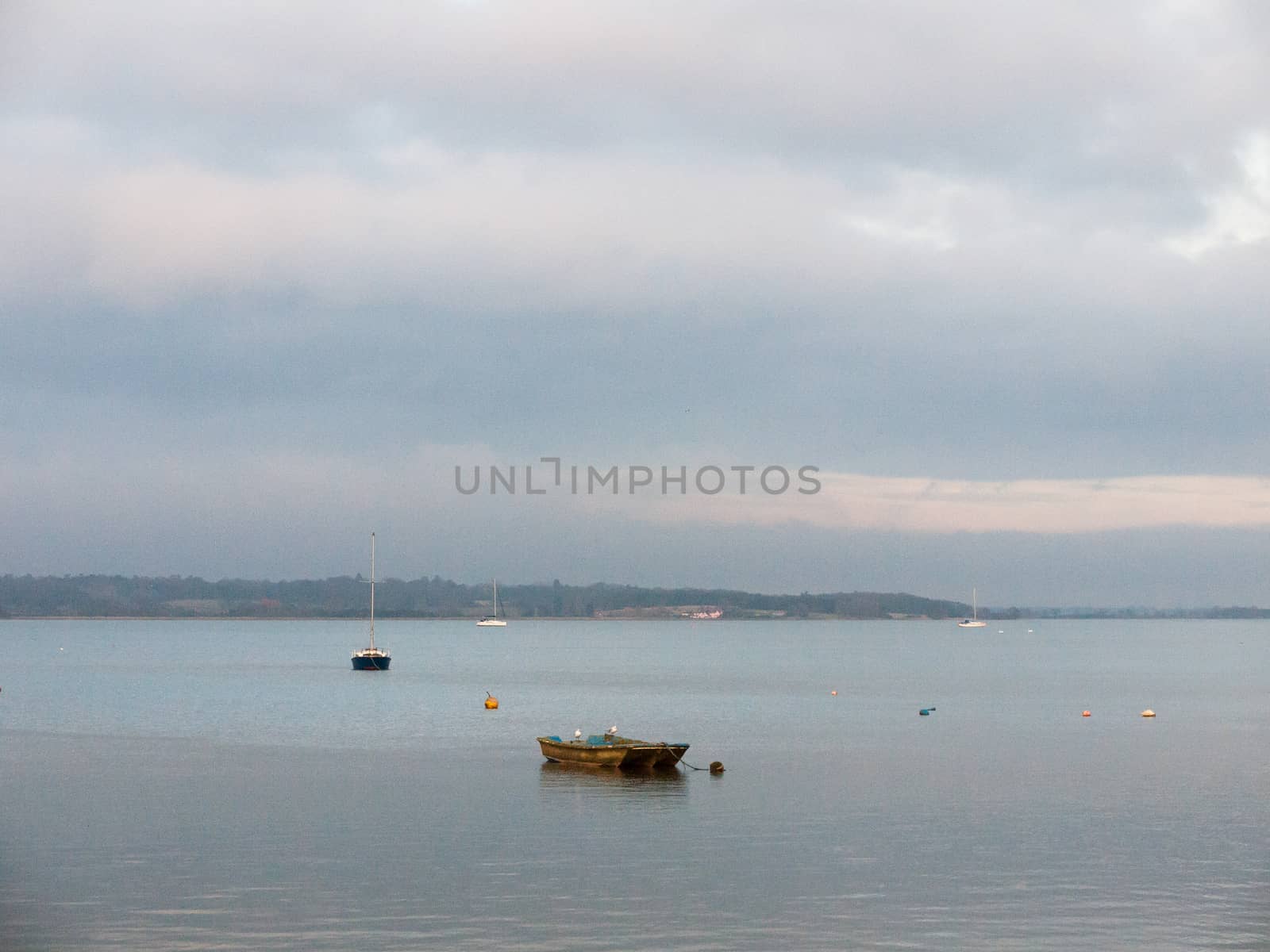 sunset over coast ocean bay water sky sea boats docks moored; essex; england; uk