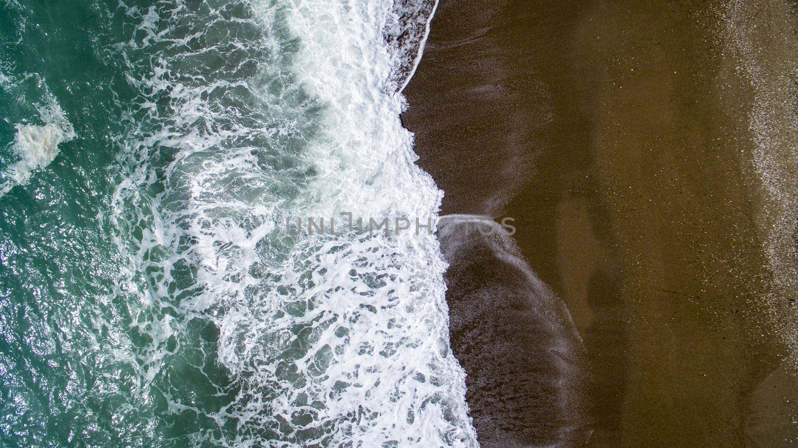 Aerial view waves break on white sand beach. by oaltindag