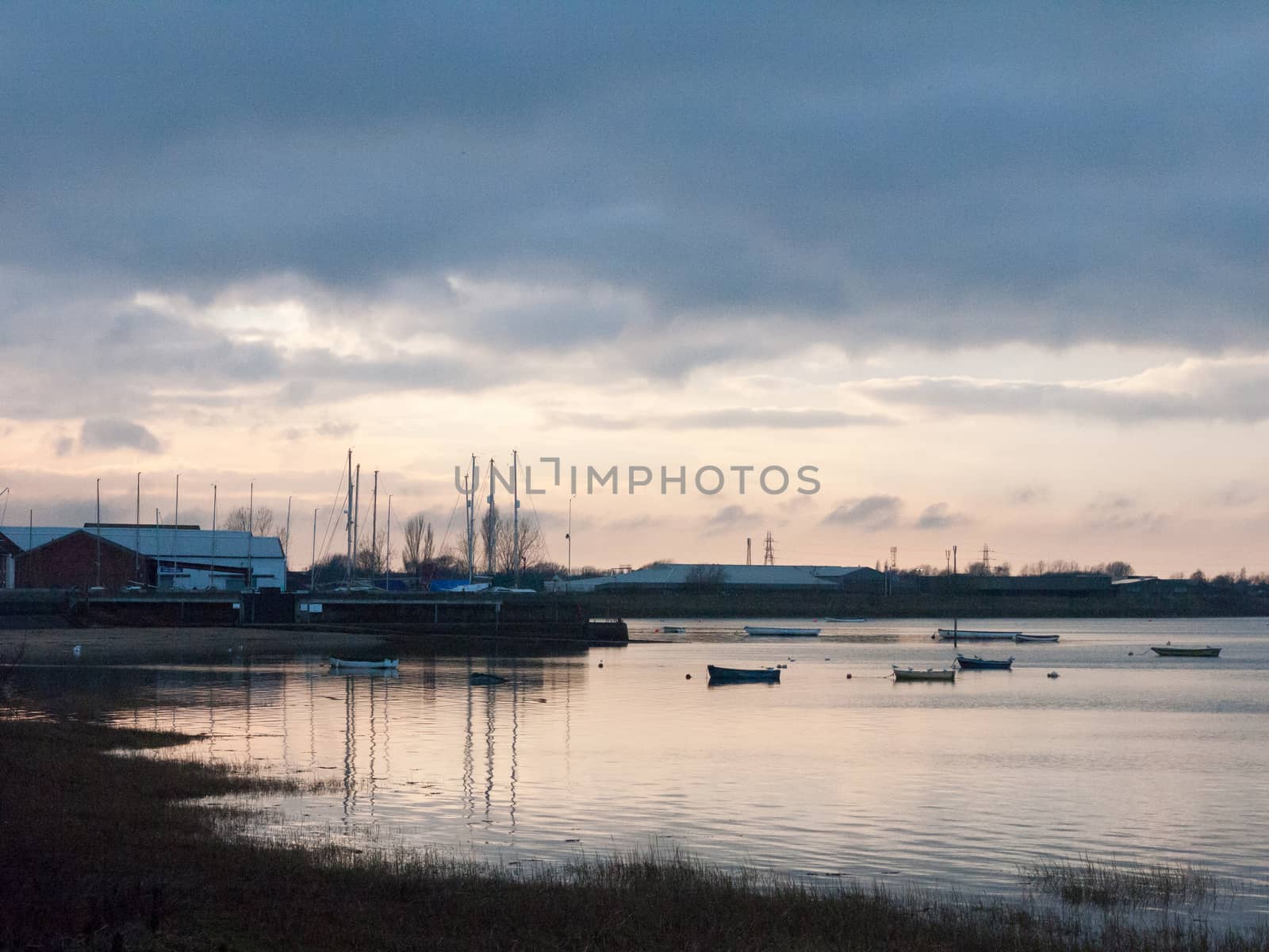 sunset over coast ocean bay water sky sea boats docks; essex; england; uk