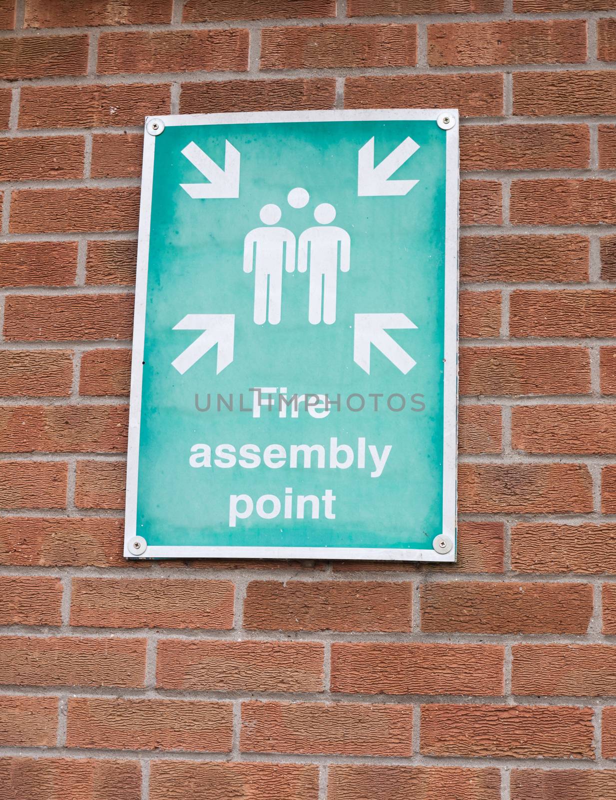 green and white fire assembly point sign on brick wall by callumrc