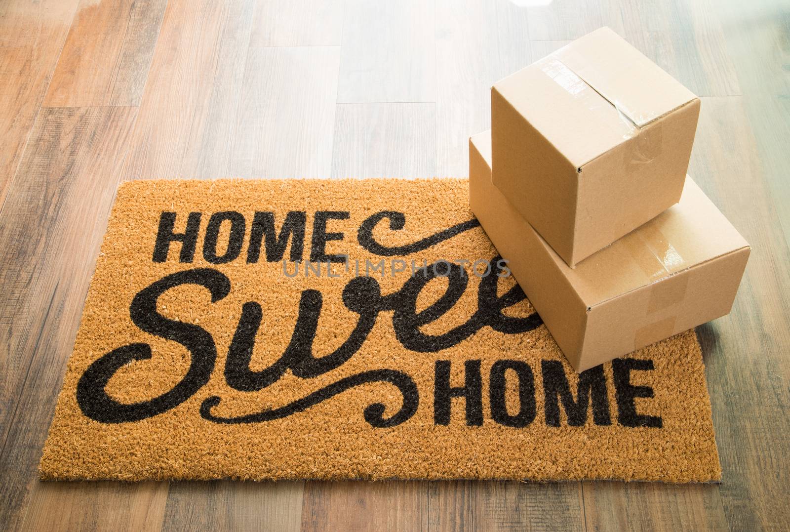 Home Sweet Home Welcome Mat On Wood Floor With Shipment of Boxes.