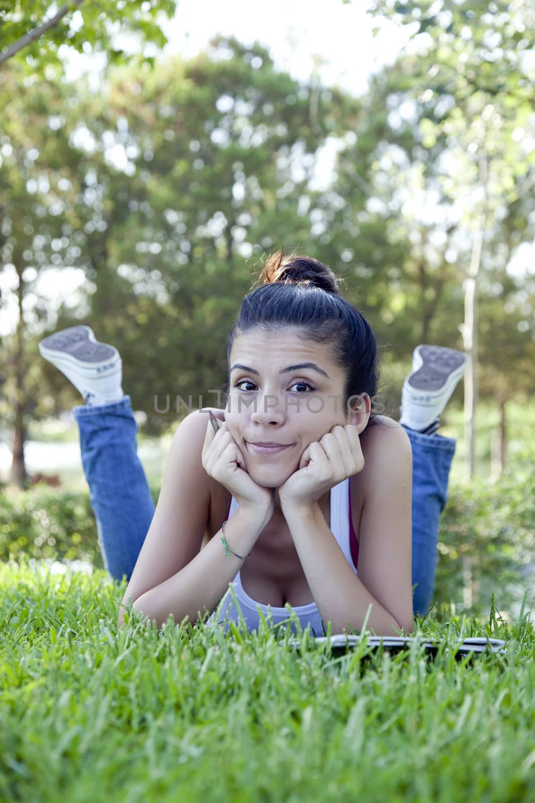 Jolly beautiful teenage girl sitting on grass.