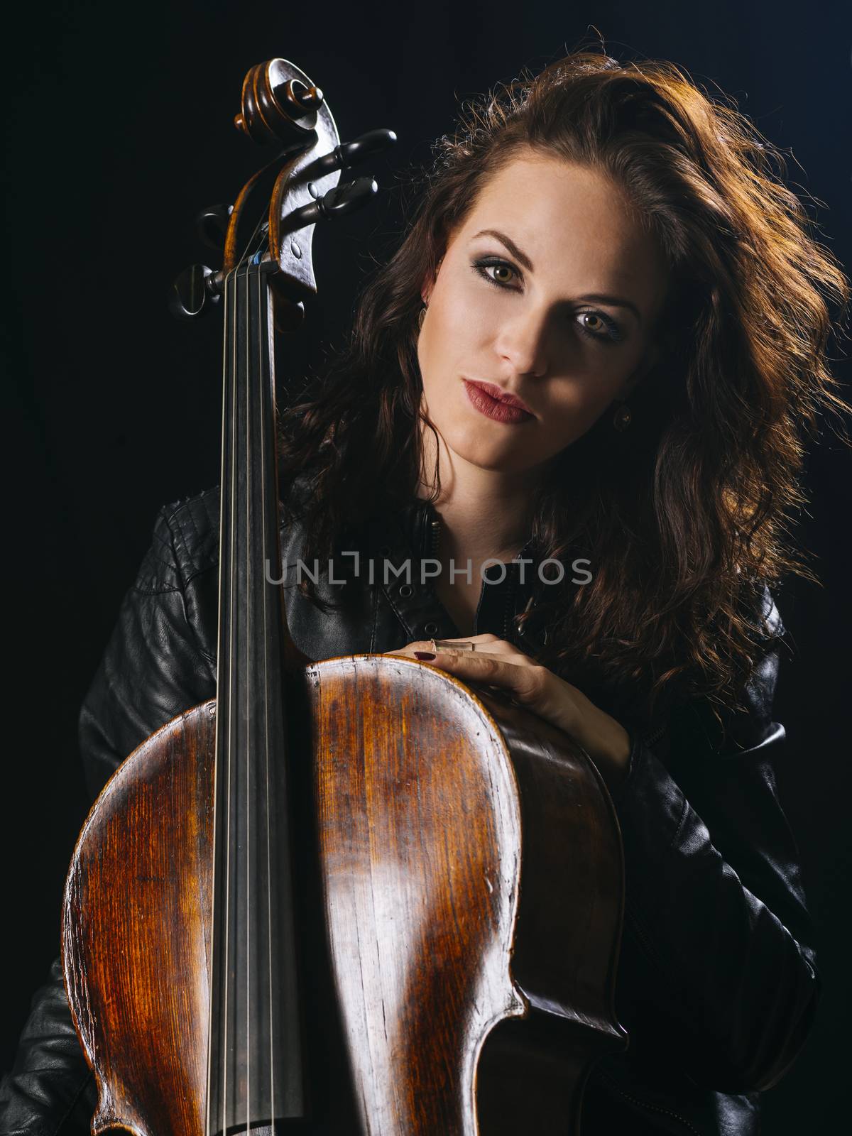 Photo of a beautiful woman posing with her old cello.