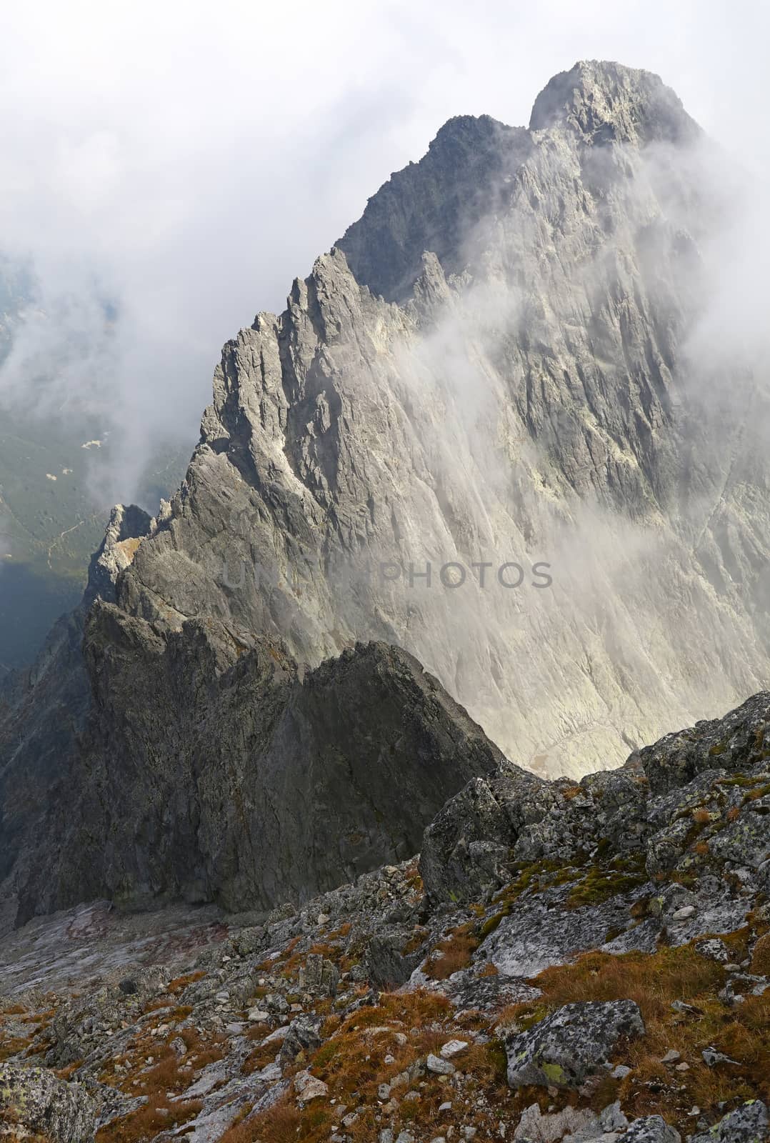 Landscape of dark rocky mountain ridge silhouette in foggy clouds, High Tatra mountains