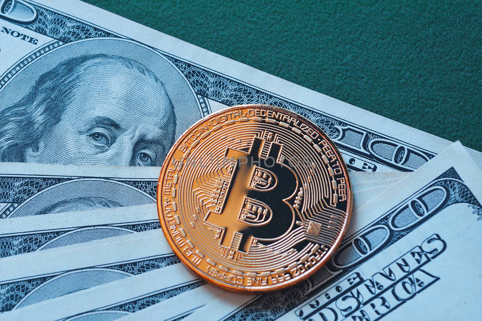 Gold Bitcoin on hundred dollars bill macro shot.