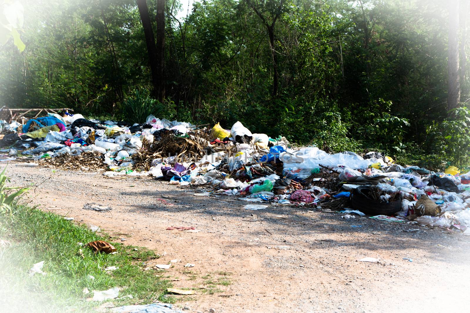 Pile of domestic garbage near the country road on nature background.