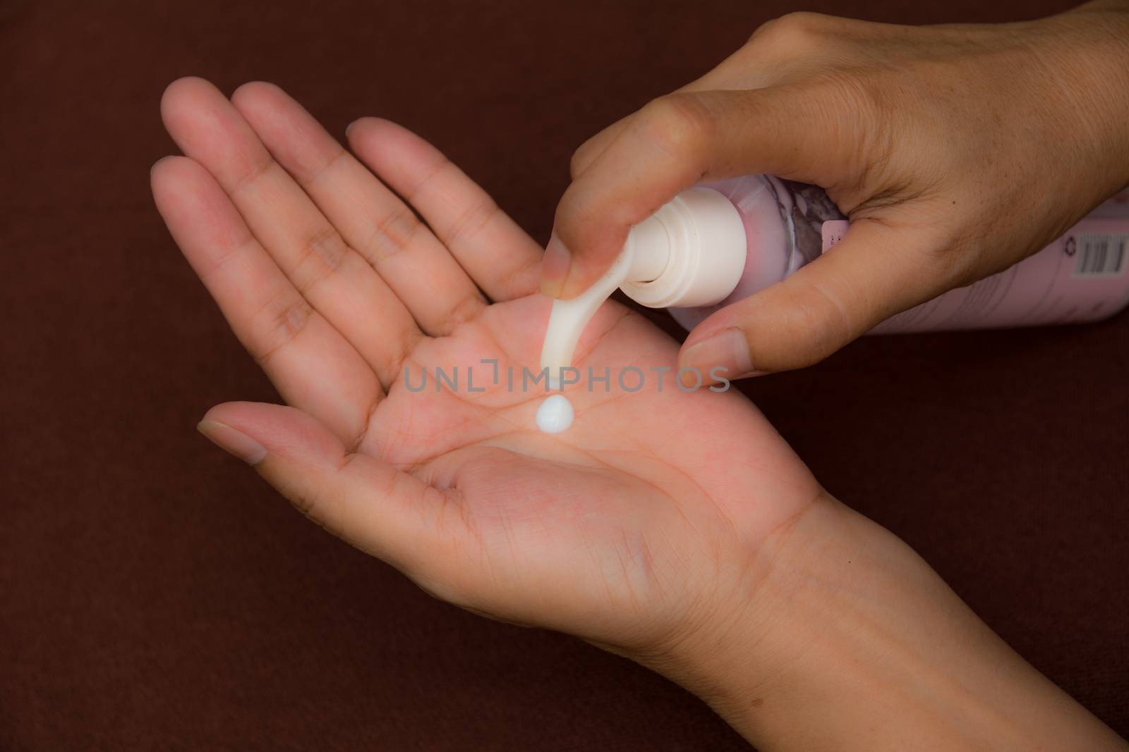 Hand of female holding sunscreen and squeeze into hand