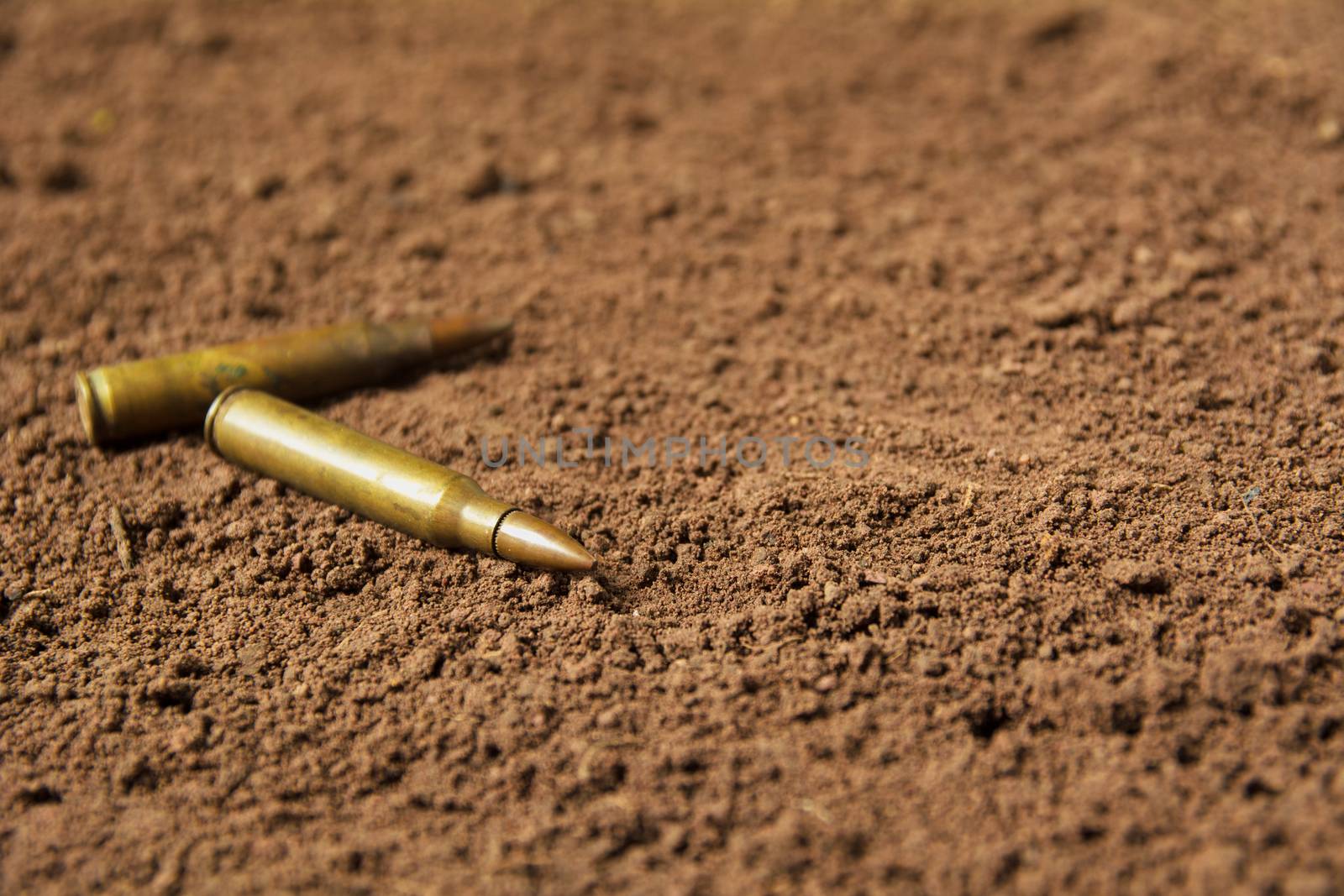 Two bullets, machine gun bullets on soil background by kirisa99