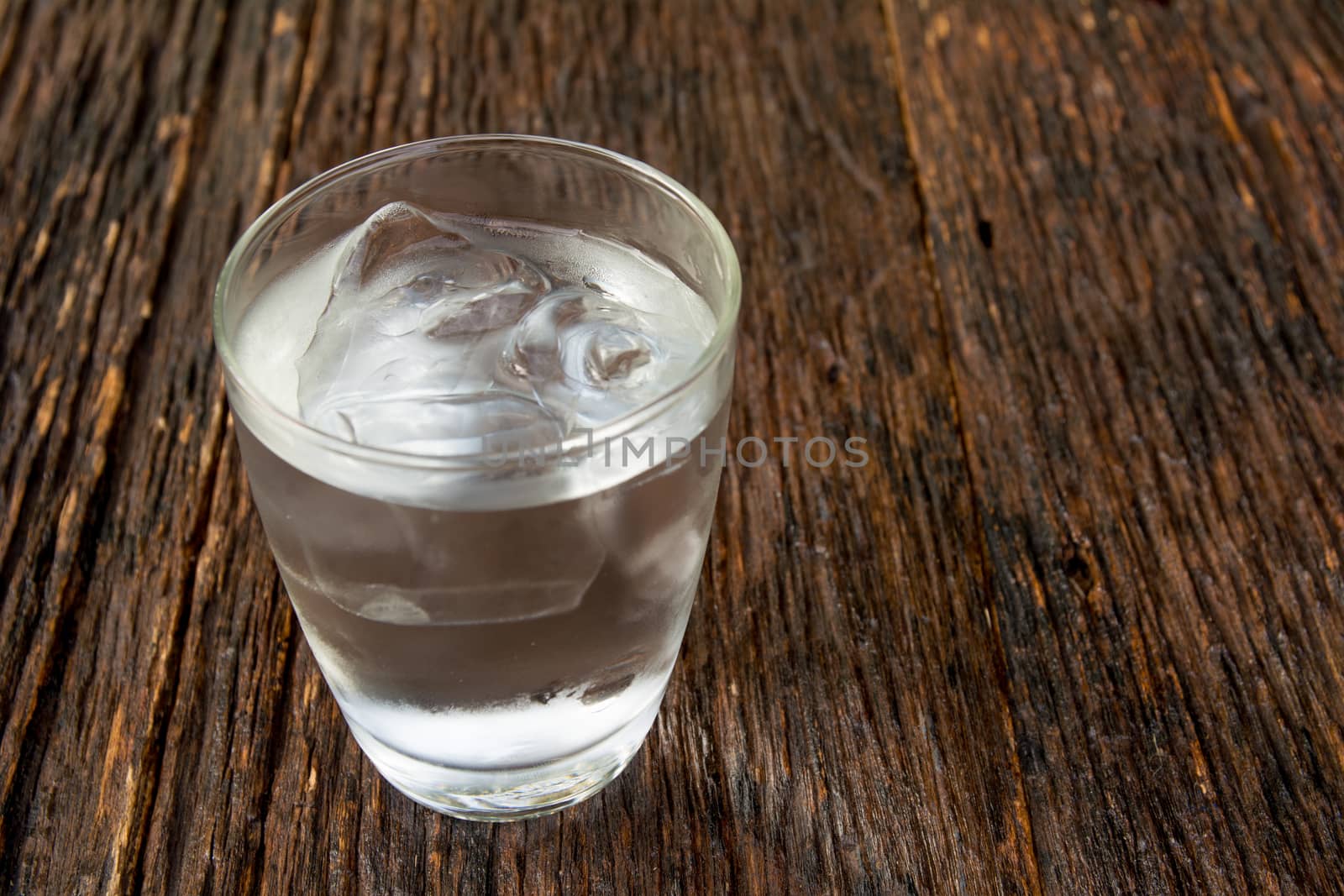 Ice cold water in glass on wooden table for healthy