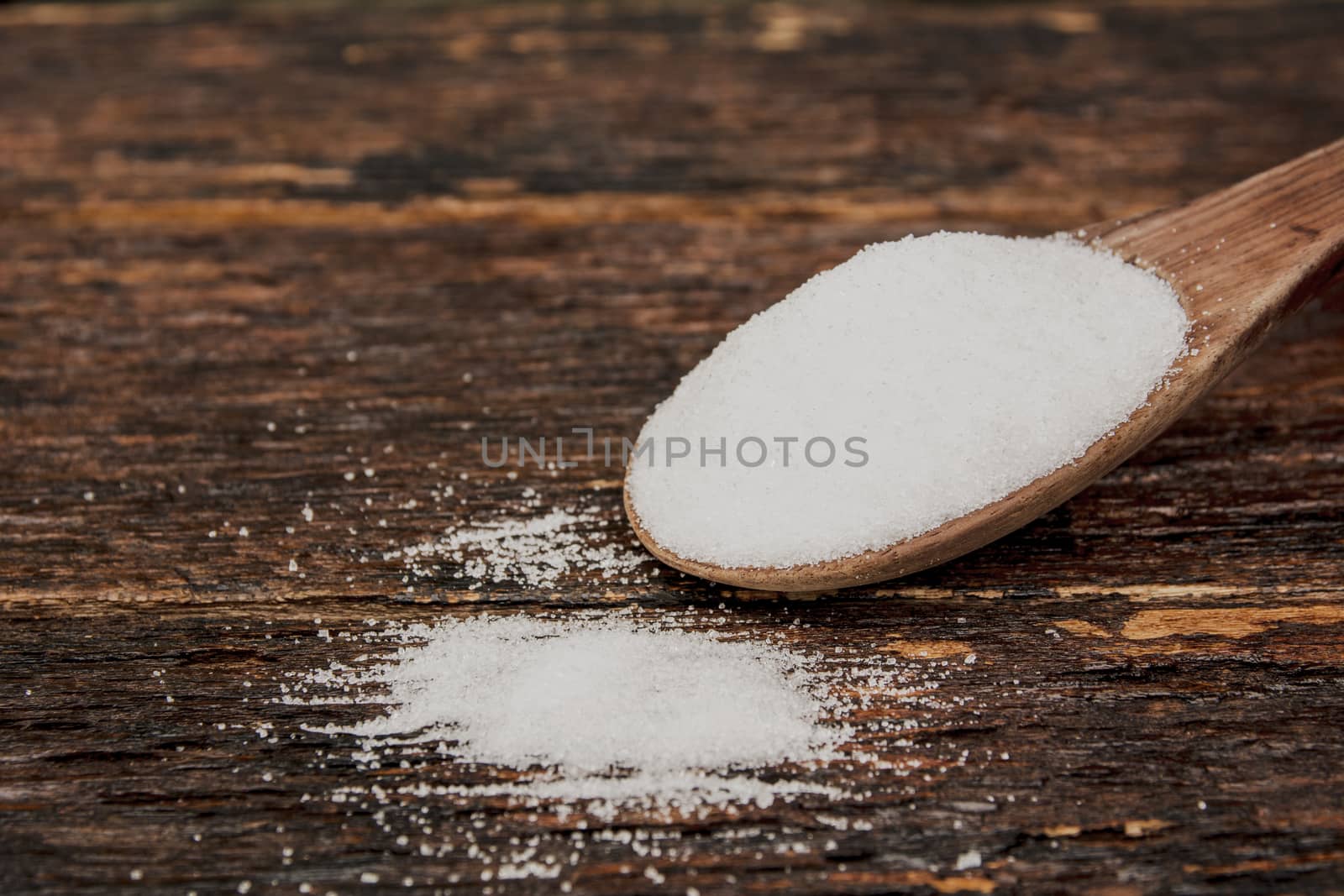 Sugar on a wooden spoon on wooden table 