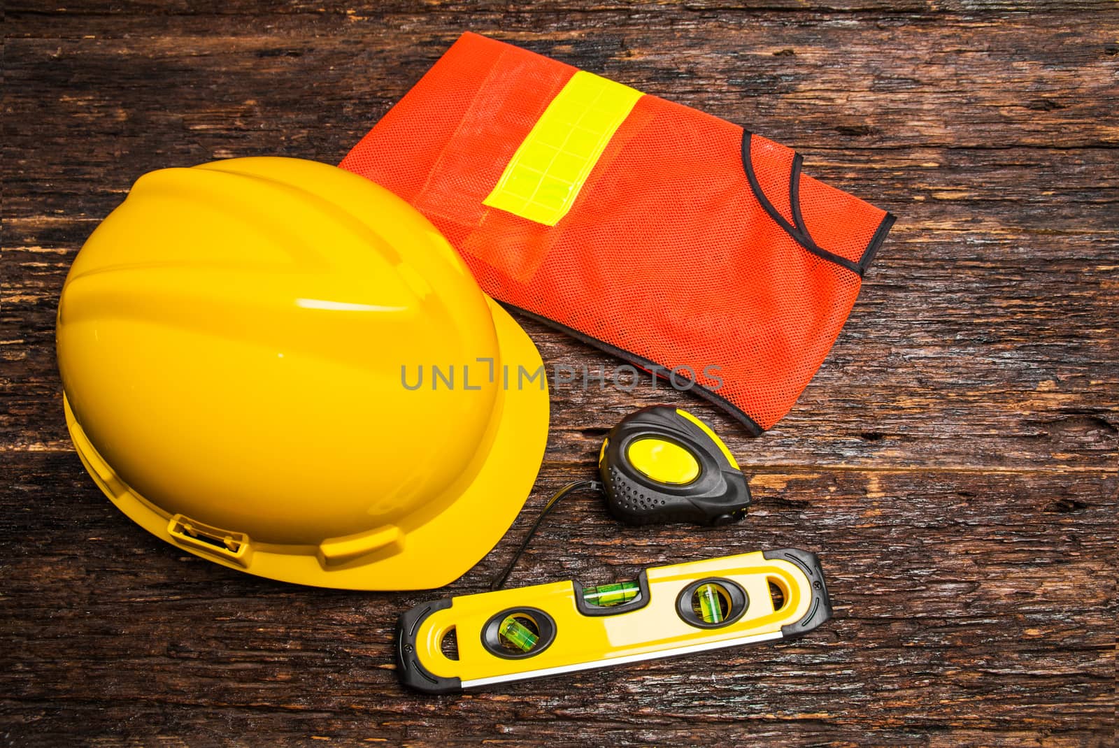 Construction tools or safety equipment with yellow helmet on wooden table.