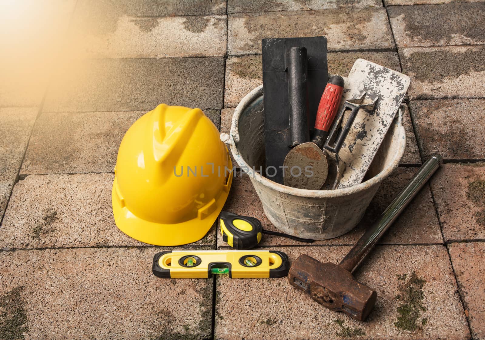 Construction tools or safety equipment with yellow helmet on brick ground