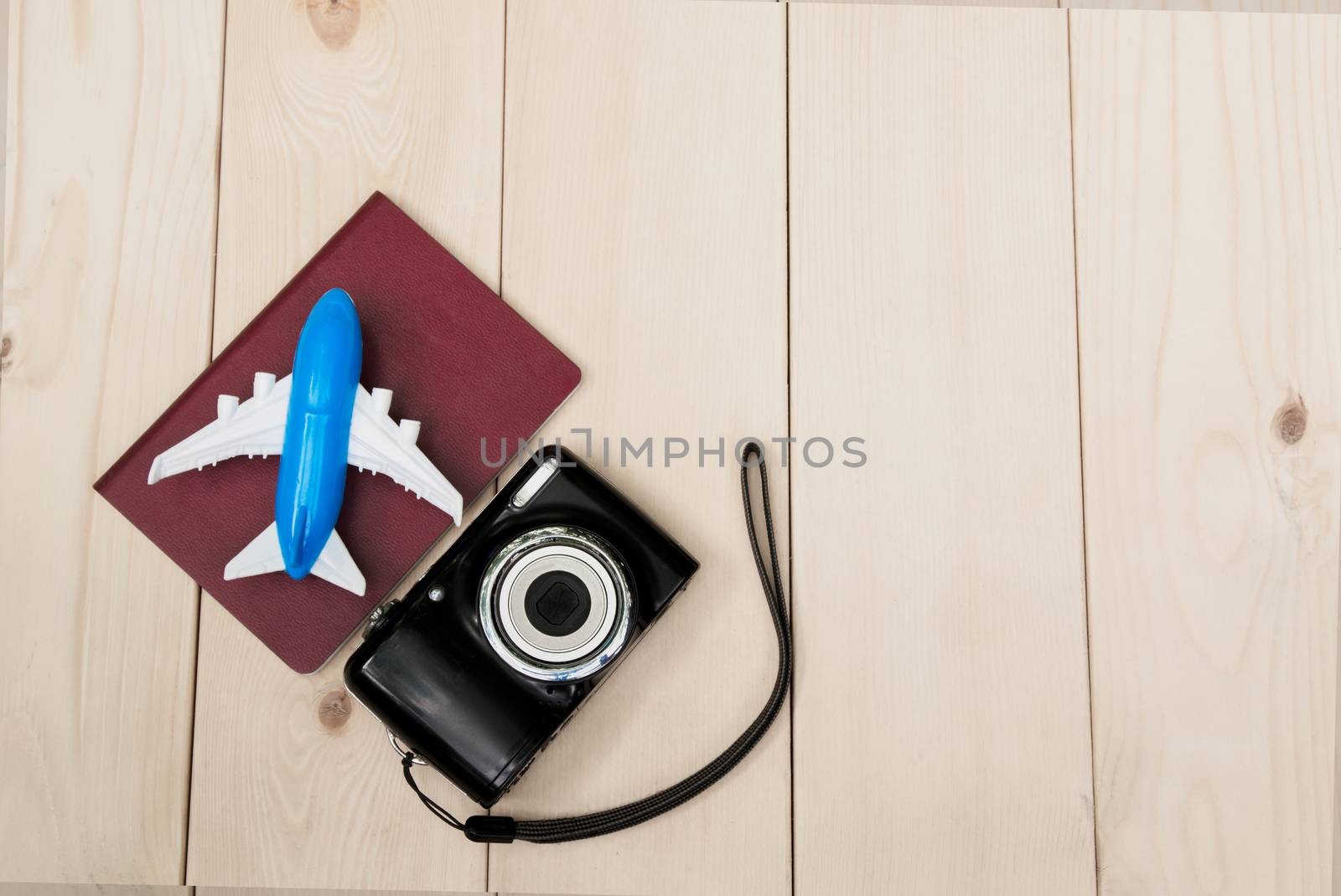 Camera with air plane and notebook for travel wooden table background. Top view with copy space.