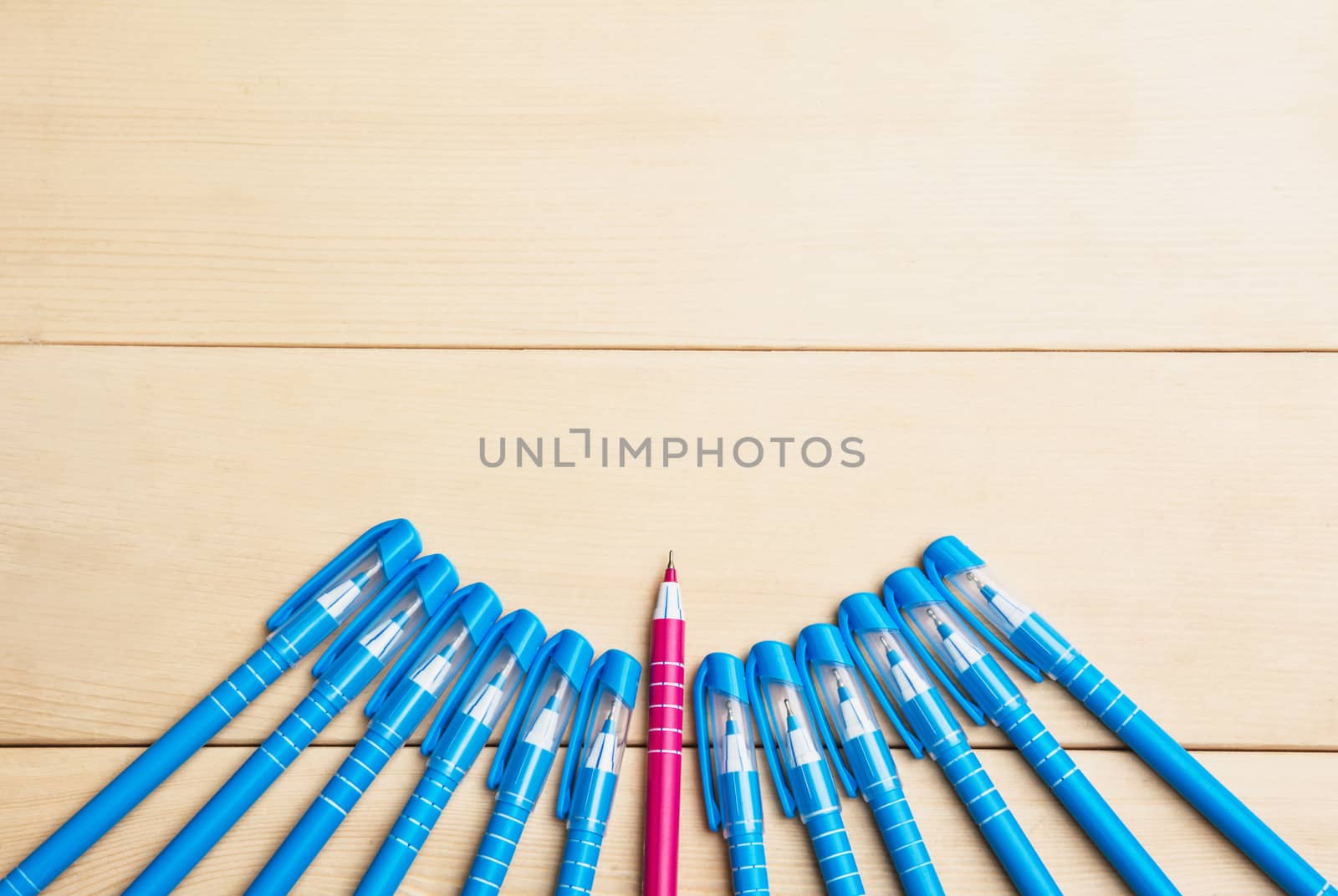 pens or writing tools on wooden table and red pen middle among blue top view